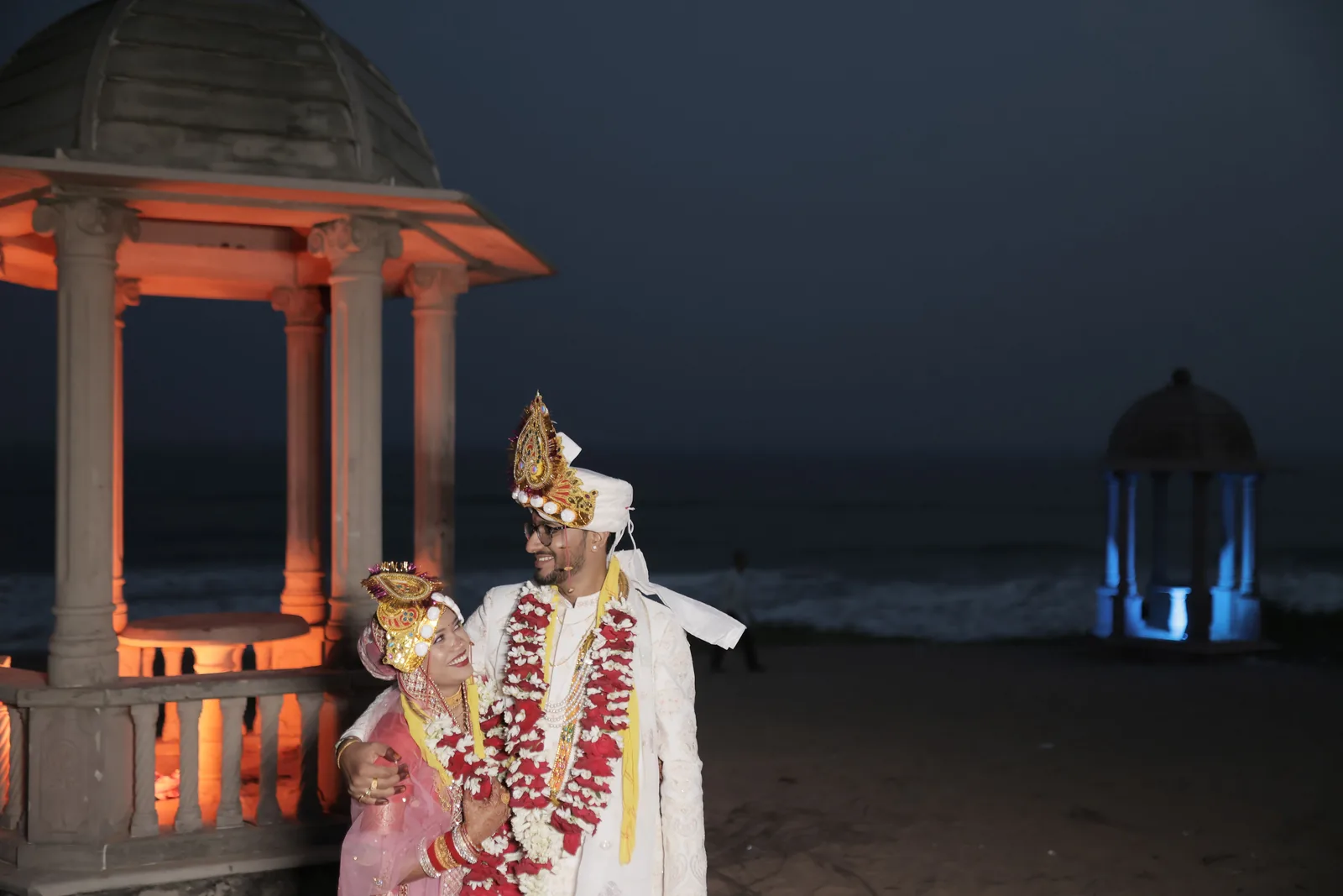 Bride and groom under a seaside gazebo at blue hour