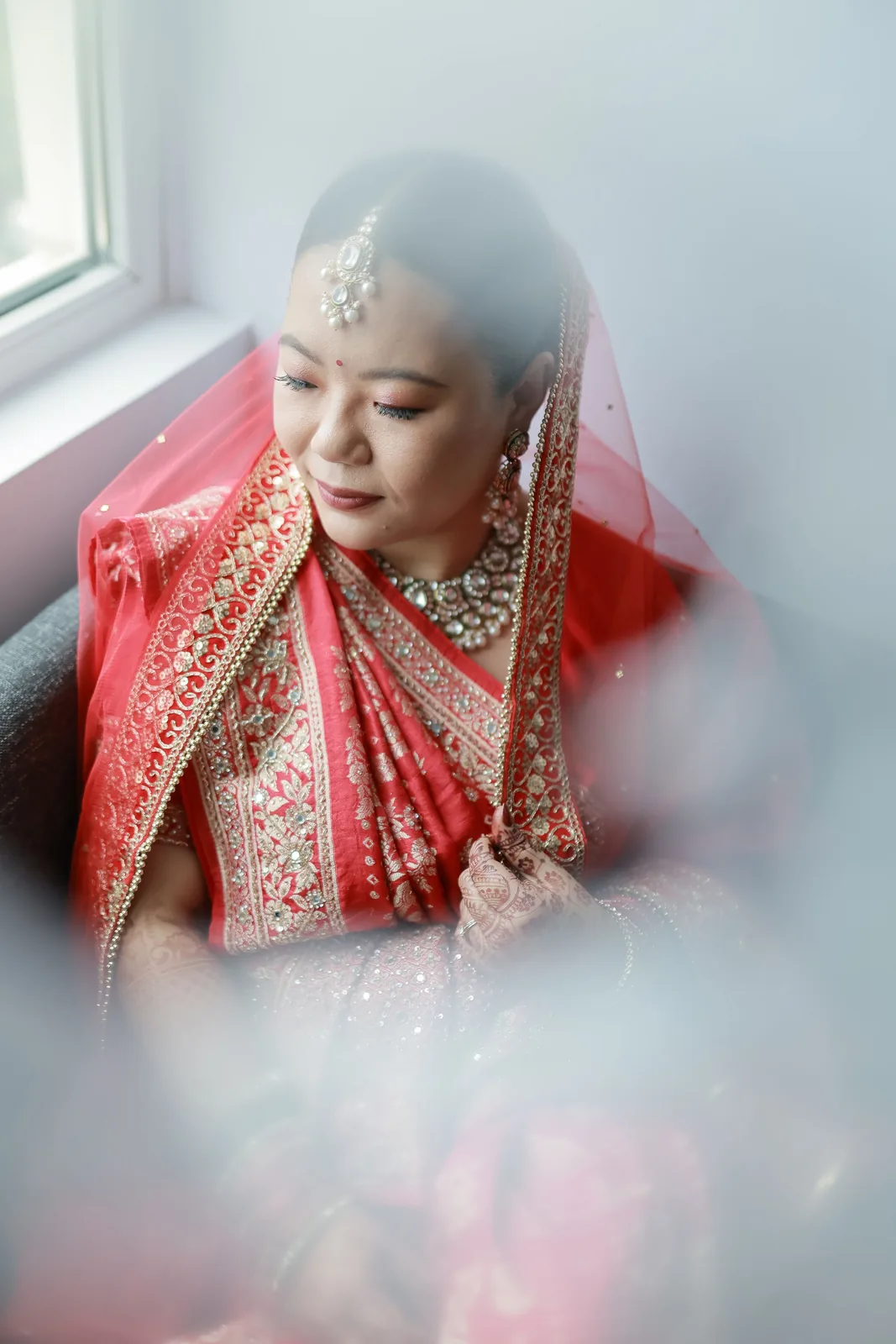 Bride in a red veil by a window