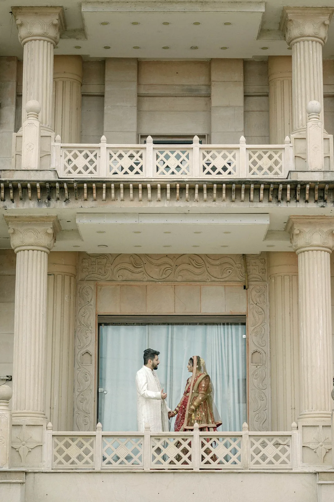 Bride and groom on a palace balcony seen from below